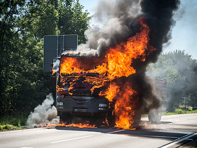 Ein brennender Lkw auf der Straße, umgeben von dichter schwarzer Rauchwolke.