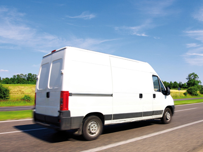 Ein weißer Lieferwagen, der auf einer Landstraße fährt.