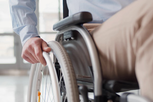 Ein Teil eines Rollstuhls mit einer Hand, die das Rad greift.