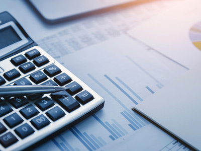 Ein Taschenrechner, ein Stift und Grafiken auf Tabellenblättern.