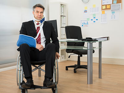 Ein Mann im Rollstuhl trägt einen Anzug und hat einen Arm in einer Schlinge.