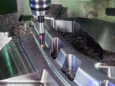 Ein Fräser bearbeitet ein Metallteil, um präzise Formen und Konturen zu erzeugen. Späne liegen auf der Fläche.