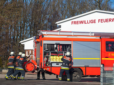 Feuerwehrleute ziehen Ausrüstung aus einem Feuerwehrauto.