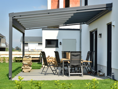 Eine moderne Terrasse mit einem überdachten Bereich, einem Tisch und Stühlen sowie Holzlager.