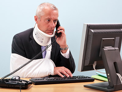 Ein Mann im Anzug mit Halskrause und Armverband, der am Telefon spricht und an einem Computer arbeitet.