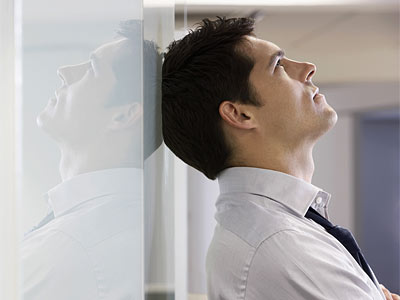 Ein Mann lehnt mit dem Kopf an einer Wand und schaut nach oben.