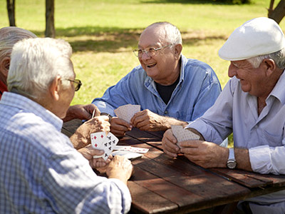 Ältere Männer spielen Karten am Tisch im Freien.