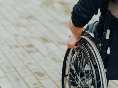 Eine Person im Rollstuhl, die das Rad greift.