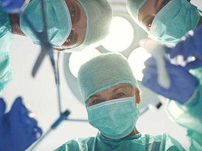 Drei Chirurgen in OP-Kleidung schauen in die Kamera.