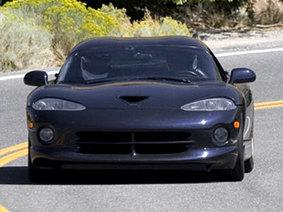 Ein schwarzer Sportwagen fährt auf einer kurvenreichen Straße.