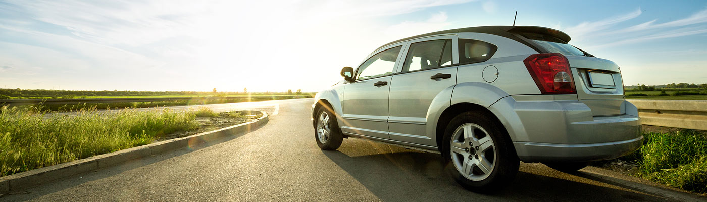 Ein silbernes Auto auf einer Straße bei Sonnenuntergang.