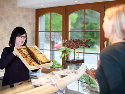 Eine Frau reicht einer anderen Frau eine Schachtel mit Gebäck an der Rezeption.