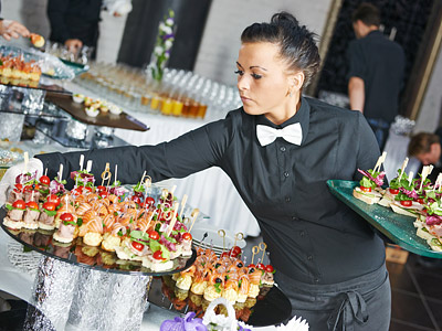 Eine Kellnerin serviert Häppchen auf einem Buffet.
