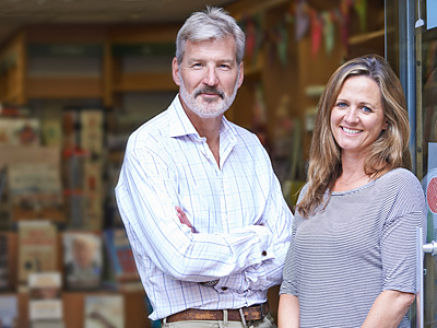 Zwei Personen stehen lächelnd vor einem Geschäft.