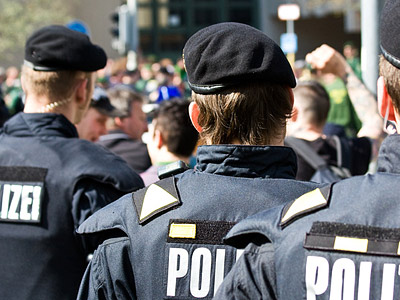 Polizisten, die einer Menschenmenge gegenüberstehen.