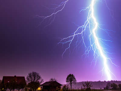 Ein blitzschlag über einer ländlichen Landschaft bei Nacht.