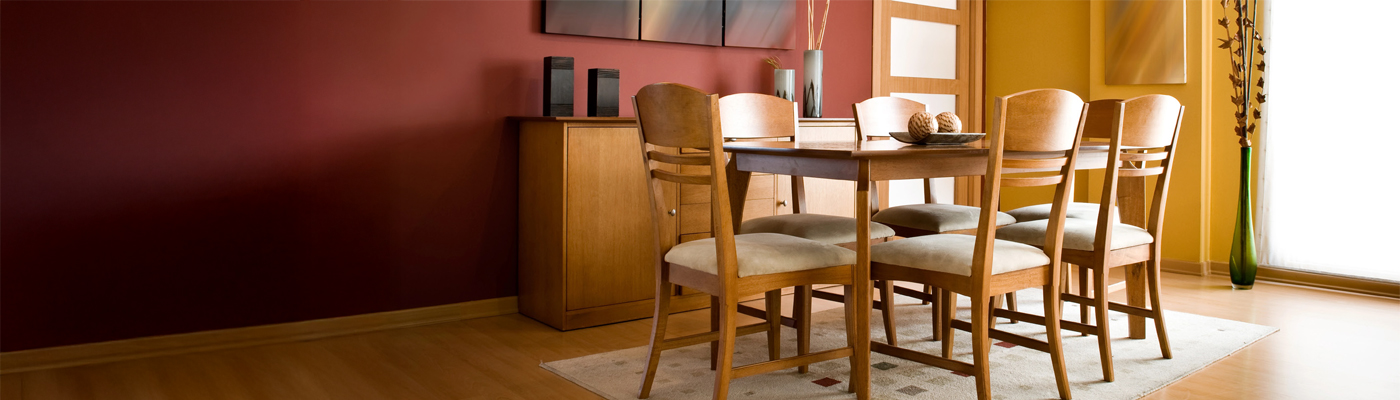 Ein Esszimmer mit einem Holztisch, Stühlen und einem Sideboard vor einer rot-gelben Wand.