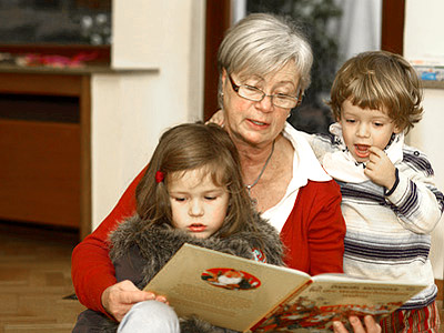 Eine Großmutter liest einem Mädchen und einem Jungen vor.