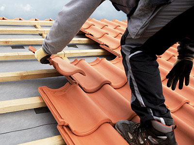 Ein Handwerker verlegt Dachziegel auf einem Dach.