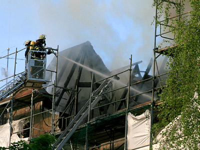 Feuerwehrleute löschen einen Brand auf einem Baugerüst.