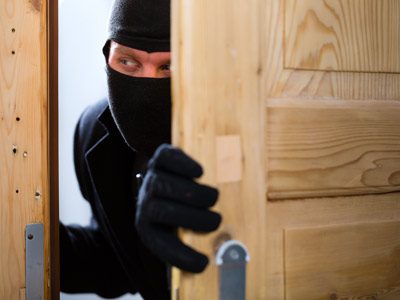 Ein maskierter Mann blickt vorsichtig hinter einer offenen Tür.