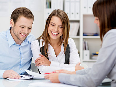 Drei Personen sitzen an einem Tisch und besprechen Unterlagen.