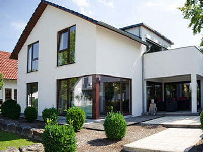 Modernes zweistöckiges Haus mit großen Fenstern und einem Garten.