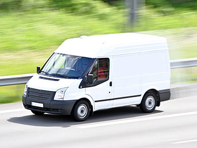 Ein weißer Lieferwagen fährt auf einer Autobahn.