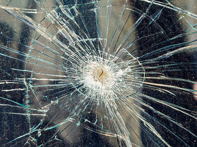 Ein zerbrochenes Glas mit Rissen, die strahlenförmig vom Zentrum ausgehen.