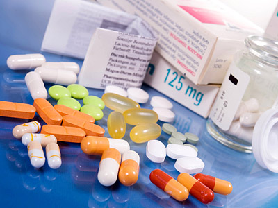 Eine Auswahl von Medikamenten in Tablettenform, einschließlich unterschiedlich gefärbter Kapseln und einer Arzneimittelverpackung.