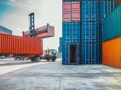 Containerterminal mit Lkw und gestapelten Frachtcontainern.