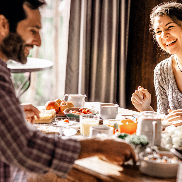 Zwei Personen genießen ein Frühstück am Tisch, umgeben von verschiedenen Speisen und Getränken.