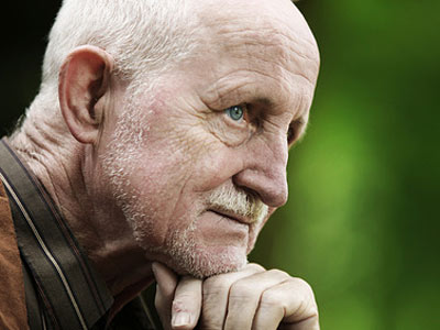 Ein älterer Mann mit grauem Haar und Bart, der nachdenklich schaut.