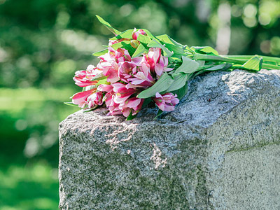 Ein Strauß pinker Blumen liegt auf einem Grabstein.