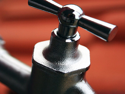 Ein metallener Wasserhahn mit einem drehbaren Griff.