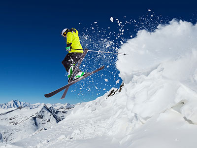 Ein Skifahrer springt über einen Schneehang in den Bergen.